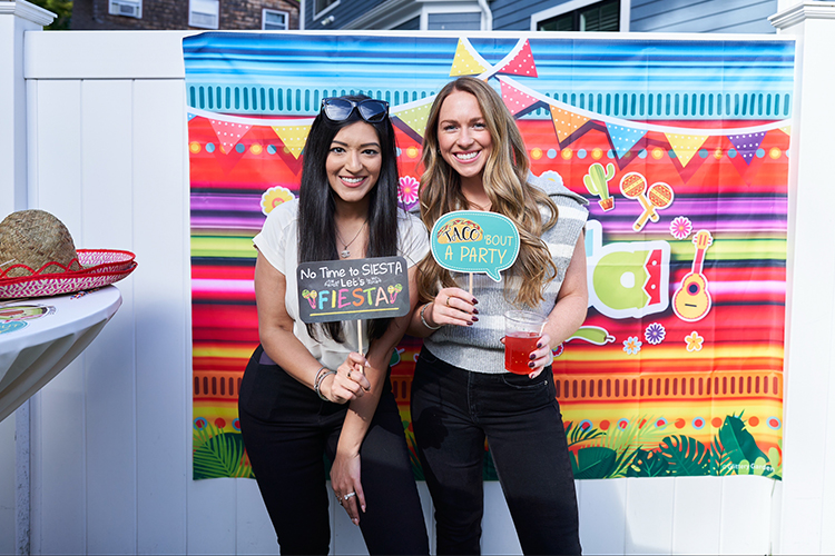 Two people posing with props in front of colorful graphics