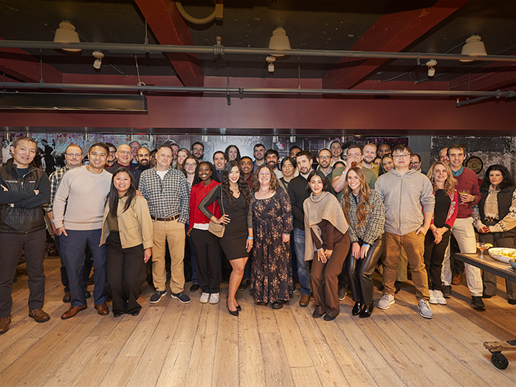 Large group posing at ping pong holiday party.